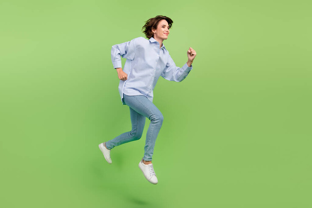 Full body photo of cheerful young happy woman jump up run empty space sale isolated on green color background - Фото, изображение