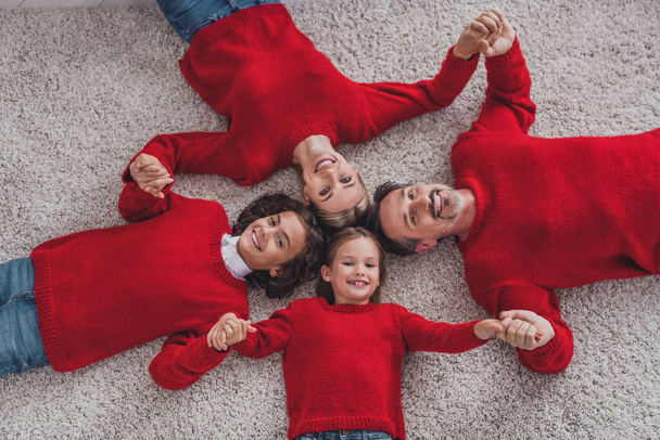 Top above high angle view of beautiful handsome cheerful adorable family lying on carpet eve spirit holding hands at home indoors - Zdjęcie, obraz