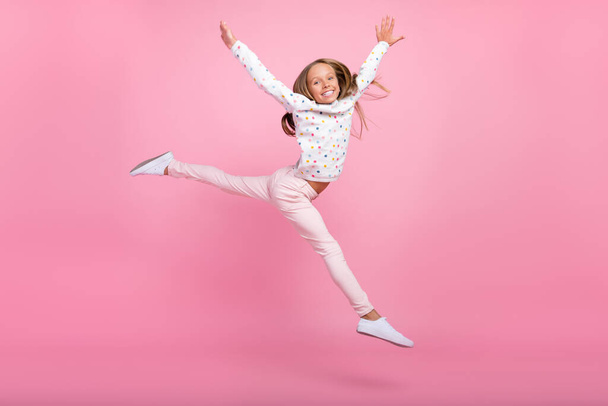 Photo of sporty energetic little lady jump raise hands wear dotted pajama pants shoes isolated pink color background - Zdjęcie, obraz