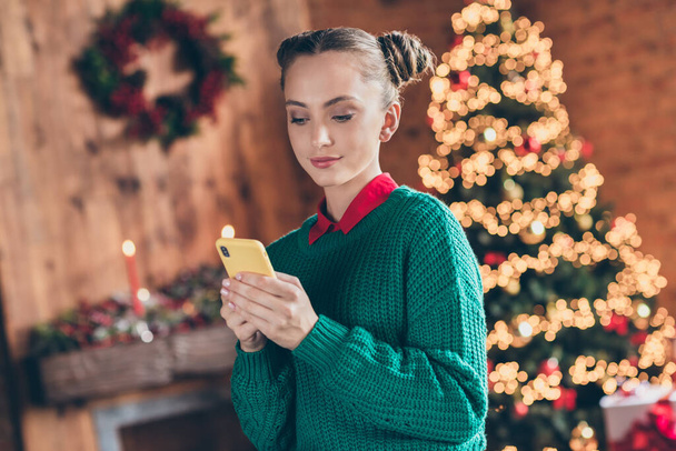Kuva melko suloinen nuori nainen pukeutunut neulotut villapaita hymyillen kirjoittamalla moderni laite joulu haluaa sisätiloissa huoneen kotitalo - Valokuva, kuva