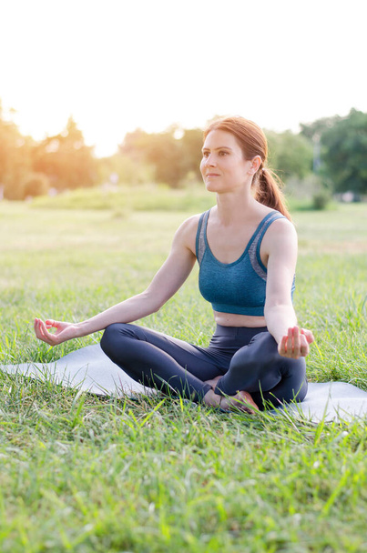 Jeune femme yogi assise en position lotus dans le parc - Photo, image