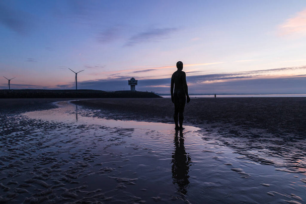 Світло починає тьмяніти на пляжі в Кросбі поблизу Ліверпуля як єдина фігура від установки Залізних Людей обличчям до моря. - Фото, зображення
