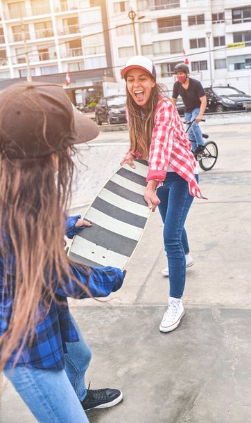 Boze meisjes vechten voor een skateboard in het skate park. vrienden die worstelen parodie. - Foto, afbeelding