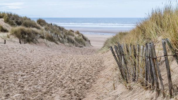 One of the main walk ways leading down between the high sand dunes to the unspoilt beach at Formby near Liverpool. - Foto, afbeelding