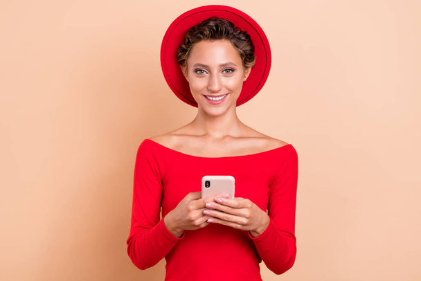 Photo of pretty positive happy young woman hold phone blogger write comment isolated on beige color background - Zdjęcie, obraz