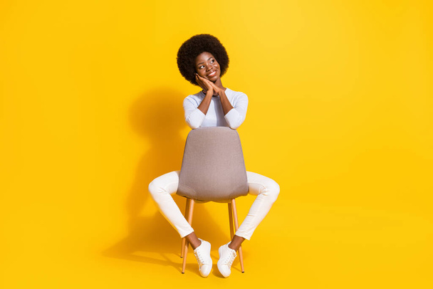 Full size photo of optimistic short hair lady hands face look empty space wear white pullover trousers sneakers isolated on yellow background - Foto, afbeelding