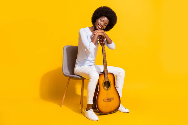 Teljes test profil fotó bájos sötét bőrű személy ül tegye a kezét a gitár elszigetelt sárga színű háttér - Fotó, kép