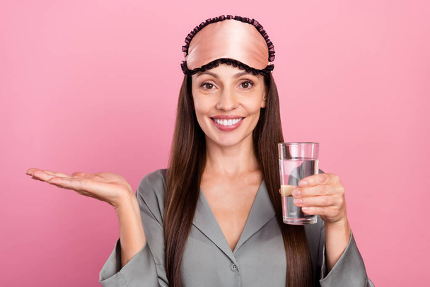 Retrato de mulher alegre atraente beber água segurando espaço cópia anúncio isolado sobre cor pastel rosa fundo - Foto, Imagem