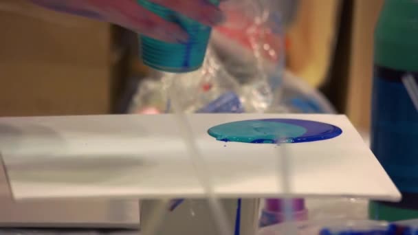 Close-up Hand gießt Farbe aus einem Plastikbecher auf eine Leinwand. - Filmmaterial, Video