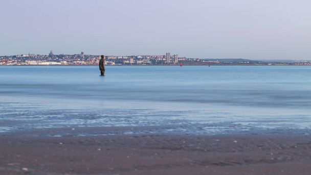 Hoog tij op Another Place, de kunstinstallatie op Crosby strand bij Liverpool bestaat uit 100 Iron Men beelden gemaakt door Antony Gormley. Dit is vastgelegd bij zonsondergang in april 2021.. - Foto, afbeelding