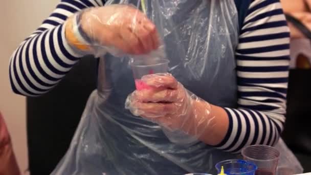 Detailní záběr ruce míchání barev v plastovém kelímku. - Záběry, video
