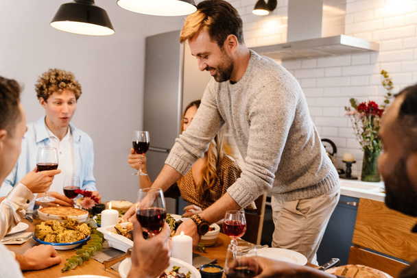 Multiracial happy friends drinking wine during thanksgiving dinner at home - Foto, Imagem