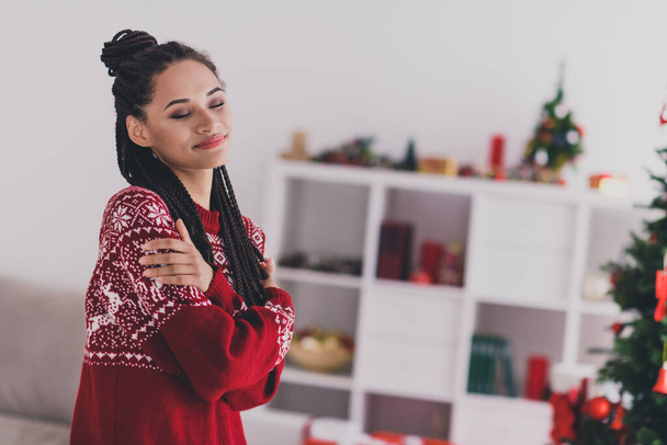 Profile side view portrait of attractive cheery dreamy girl hugging herself warm clothes festal time day serenity at home indoors - Фото, изображение