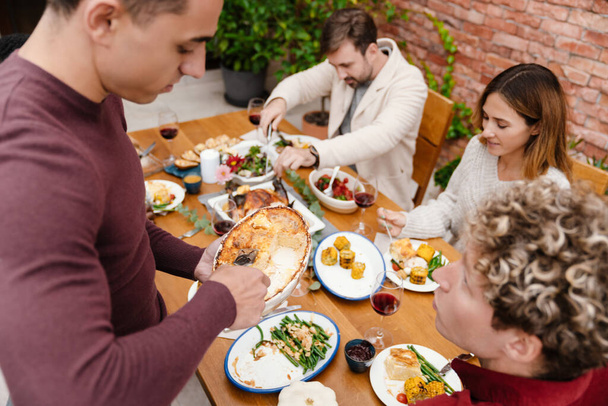 Multiracial happy friends having thanksgiving dinner on terrace outdoors - Photo, Image