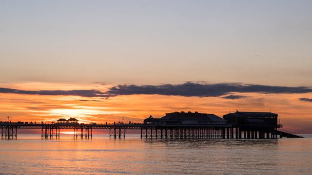 Zonsondergang achter Cromer Pier gezien op een avond in de zomer van 2021 aan de Noord-Norfolk kust. - Foto, afbeelding