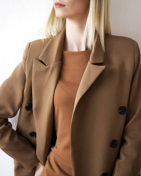 Photo de mode d'une belle jeune femme élégante dans un costume brun et beige surdimensionné posant sur fond blanc. Studio Shot. Photo verticale - Photo, image