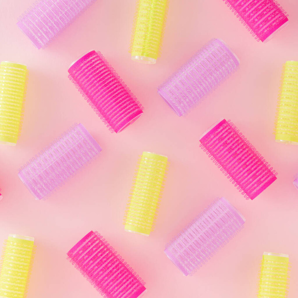 Creative pattern made of colorful hair curlers on a pastel pink background. Minimal retro fashion concept. Salons and hairstyle inspiration. - Foto, afbeelding