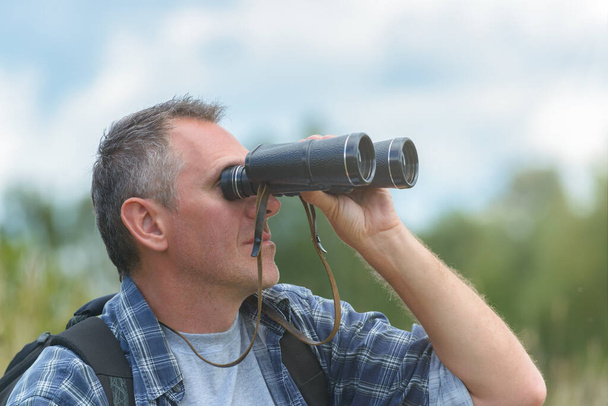 Primer plano de un hombre mirando a través de prismáticos, al aire libre. - Foto, Imagen