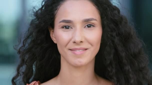 Nahaufnahme Porträt im Freien in der Stadt lockige Haare brünett hispanische ethnische gemischte Rasse Frau glücklich Modell Dame Blick in die Kamera lächelt zahm, weibliche Klientin lächelt zufrieden mit Zahnarztpraxis - Filmmaterial, Video