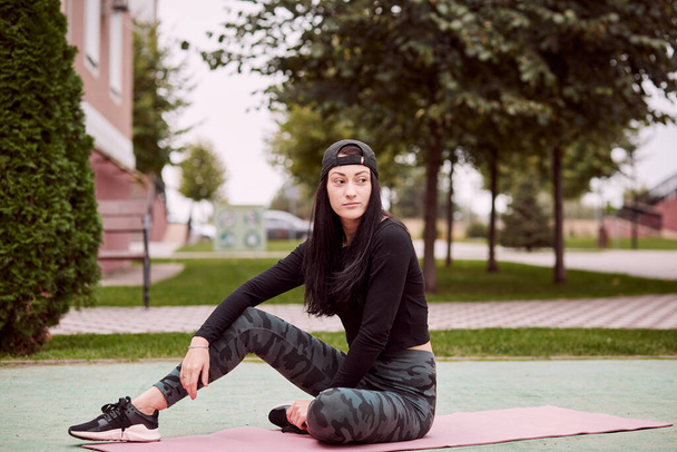 Молодая стройная женщина расслабляется после тренировки на улице. Тренировки на улице. Понятие здорового образа жизни. Высокое качество фото - Фото, изображение