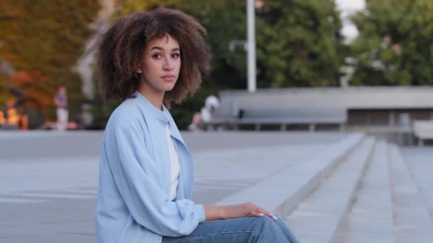 Triste chateado afro-americano estressado mulher africana com cabelo encaracolado afro angustiado senhora fêmea frustrado menina sentado ao ar livre na cidade mostrando sinal banner anúncio chamada para ajudar preocupado com o problema - Filmagem, Vídeo