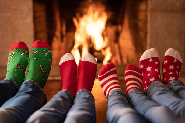 Family in Christmas socks near fireplace. Mother; father and children having fun together. People relaxing at home. Winter holiday Xmas and New Year concept - Фото, зображення
