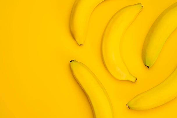 テーブルの上に新鮮な黄色のバナナ。上から見たフルーツバナナの模様。黄色の最小限の背景 - 写真・画像