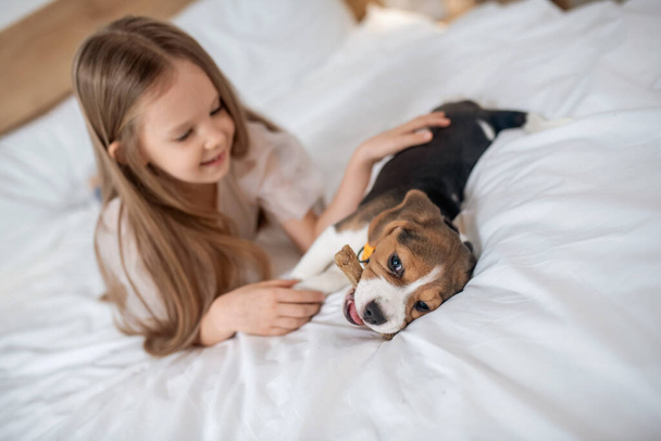 A cute girl playing with her puppy and looking happy - Photo, image