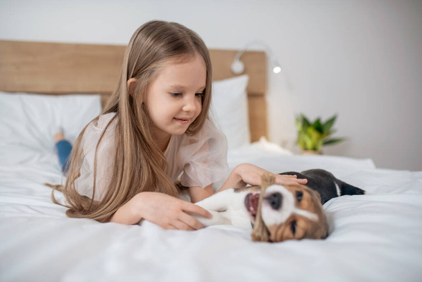 A cute girl playing with her puppy and looking happy - Fotoğraf, Görsel