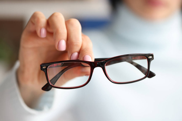 In female hand there are stylish fashionable glasses in black frames - Foto, Imagem