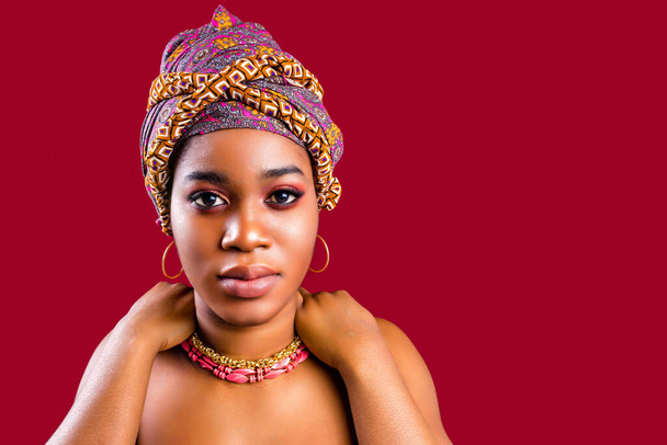 glamour dark skin woman wrapped on turban in studio in red background - Foto, Imagem
