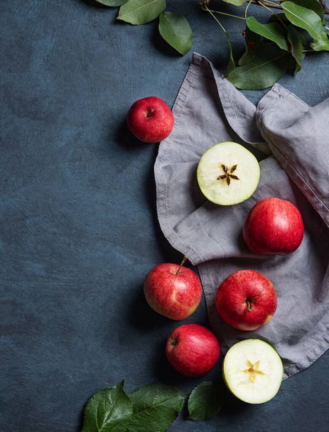 Szaftos vörös alma levelekkel, szürke szalvétán, sötétkék háttérrel. Az őszi egészséges étel fogalma. Felülnézet és másolás. - Fotó, kép