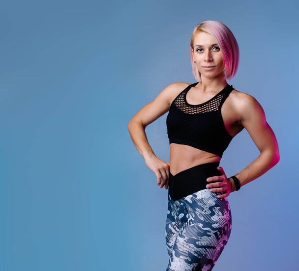 Stylish sports background. Sporty modern woman exercising strong with muscles. Blue fitness neon banner. Workout gym. Girl powerful in sportswear. Bodybuilding. Pink hair. crossfit fitness motivation  - Fotó, kép