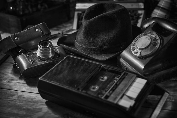Eski bir sinema sahnesi, şapka, telefon, kamera, taşınabilir kasetçalar ve viski ile birlikte dedektifin masası. - Fotoğraf, Görsel