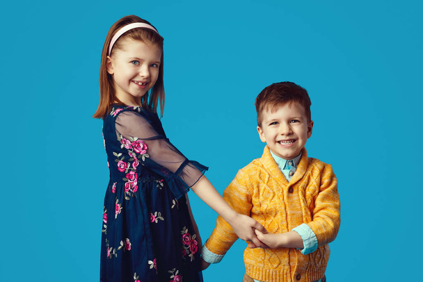 Hermana feliz en vestido azul tomados de la mano junto con su hermano pequeño - Foto, imagen