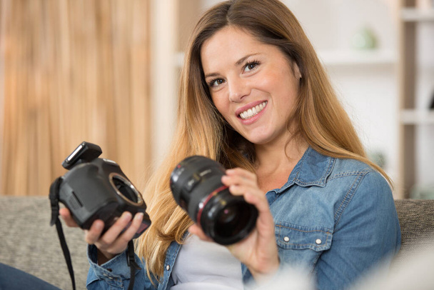 woman holding camera and the dismantled lens - Foto, Imagen