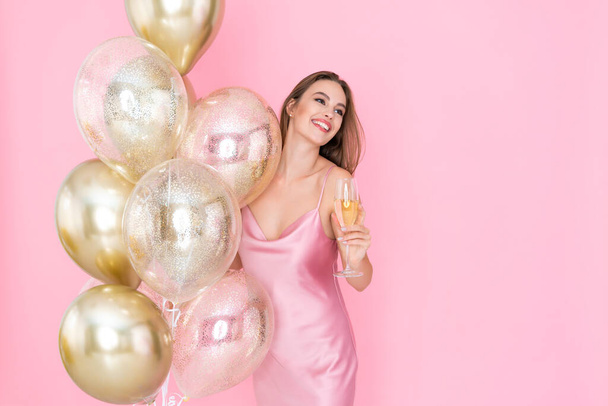 Sorridente ragazza felice tiene un bicchiere di champagne e molti palloncini d'aria. è venuto alla festa. Celebrazione  - Foto, immagini