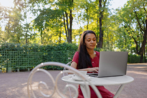 beautiful and young millennial african woman in a public place working on a laptop - Photo, image