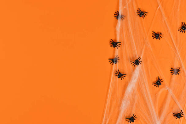 Spider webs and plastic spiders on side of orange Halloween background with copy space - Fotó, kép