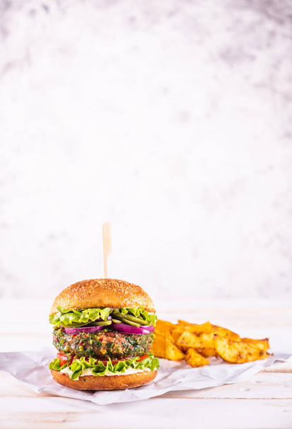 Hamburger vegano con zeppe di patate su un tavolo bianco e con sfondo bianco. Carne vegetale. Pronto da mangiare.  - Foto, immagini