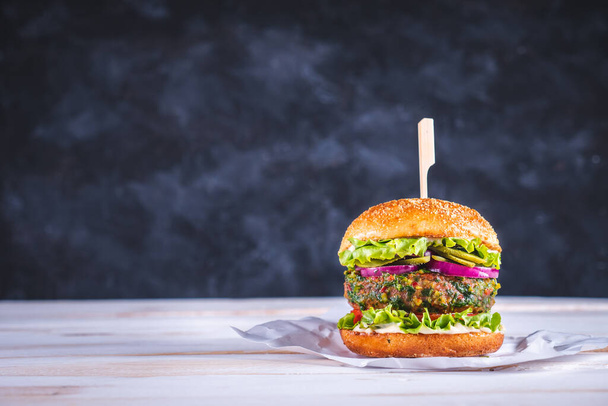 Веганський бургер на білому столі і з темно-синім тлом. Овочеве м'ясо. Готовий їсти
.  - Фото, зображення