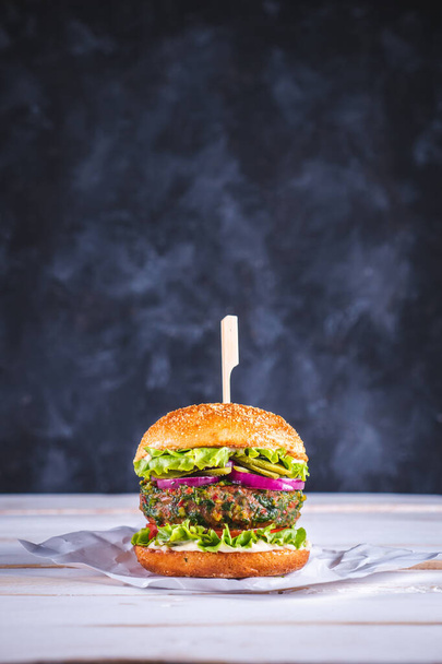 Veganistische hamburger op een witte tafel en met een donkerblauwe achtergrond. Plantaardig vlees. Klaar om te eten..  - Foto, afbeelding