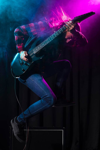 artist playing guitar jumping sideways. High quality photo - Zdjęcie, obraz
