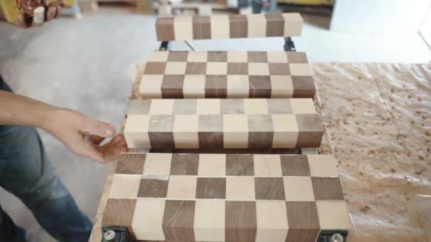 Процес склеювання деревини на виробничих потужностях, тесля, що застосовує клей для затискання дерев'яних брусків у твердій дошці. Ремісник, який працює в майстерні, робота ручної роботи в промисловості
 - Кадри, відео