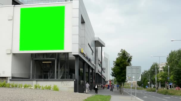 Plakatwand an einem Gebäude (Einkaufszentrum) - grüner Bildschirm - Straße mit Menschen und Straße (Autos) - bewölkter Himmel mit Natur (Bäume)) - Filmmaterial, Video