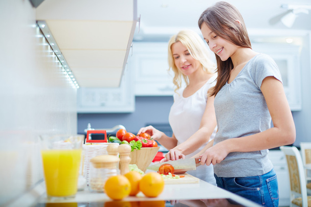 Girl and her mother cooking in kitchen - Foto, Bild