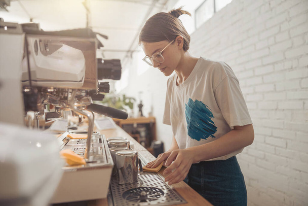 Charming female barista cleaning counter in coffee shop - Foto, Imagem