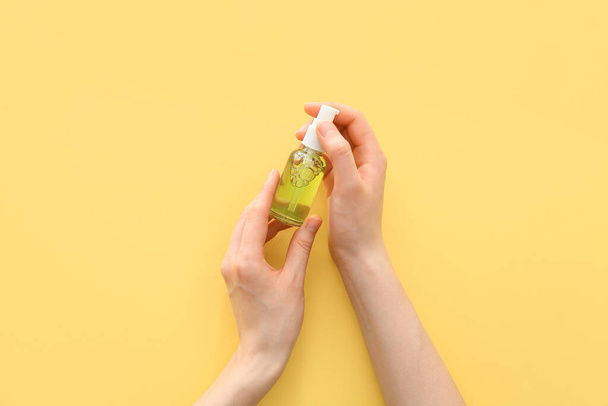 Renkli arka planda bir şişe kozmetik ürünü olan kadın - Fotoğraf, Görsel