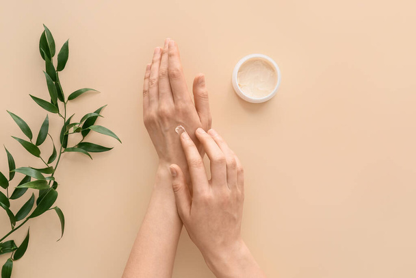 Mujer aplicando crema natural de manos sobre fondo claro - Foto, imagen