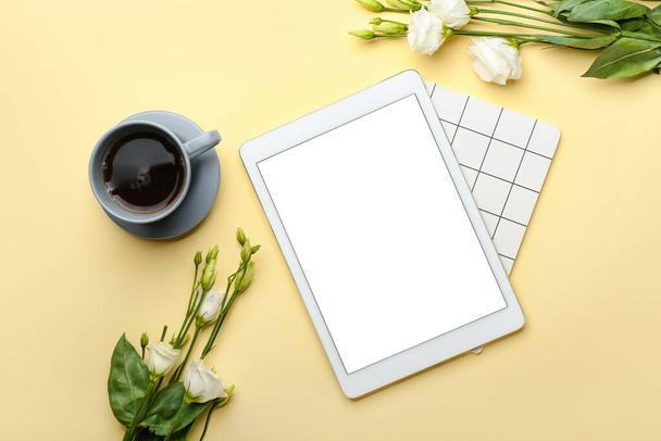 Cup of coffee, tablet computer, notebook and flowers on color background - Photo, Image